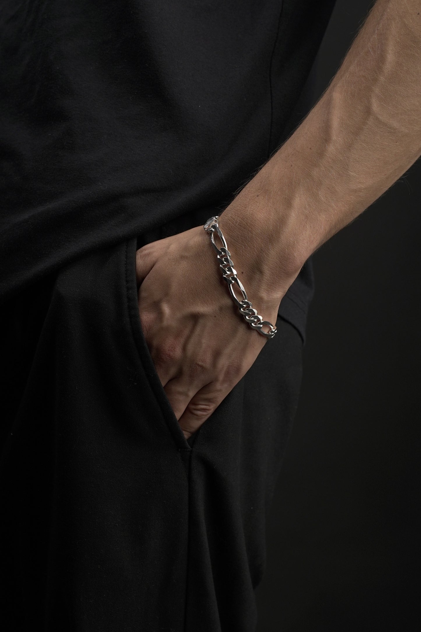 Hand wearing a bracelet on a black background
