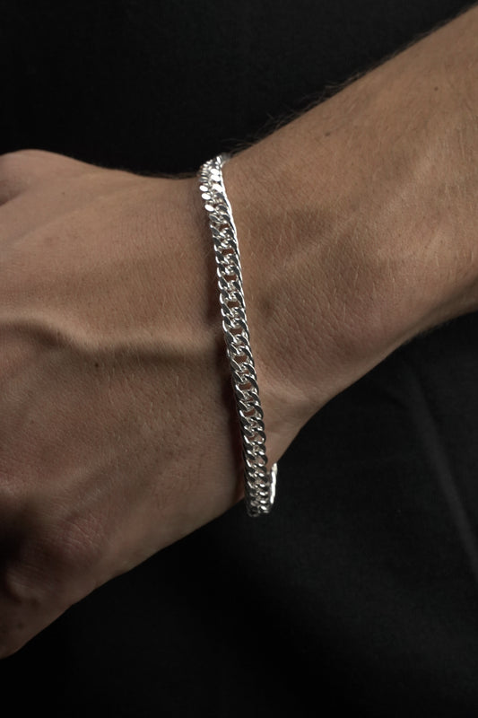 Silver chain bracelet on a wrist against a dark background