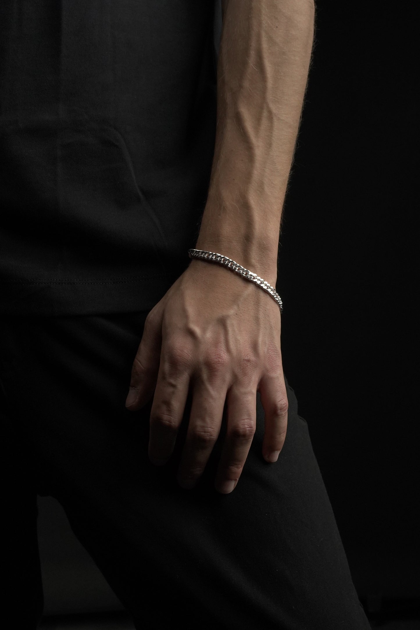 Hand wearing a bracelet on a dark background