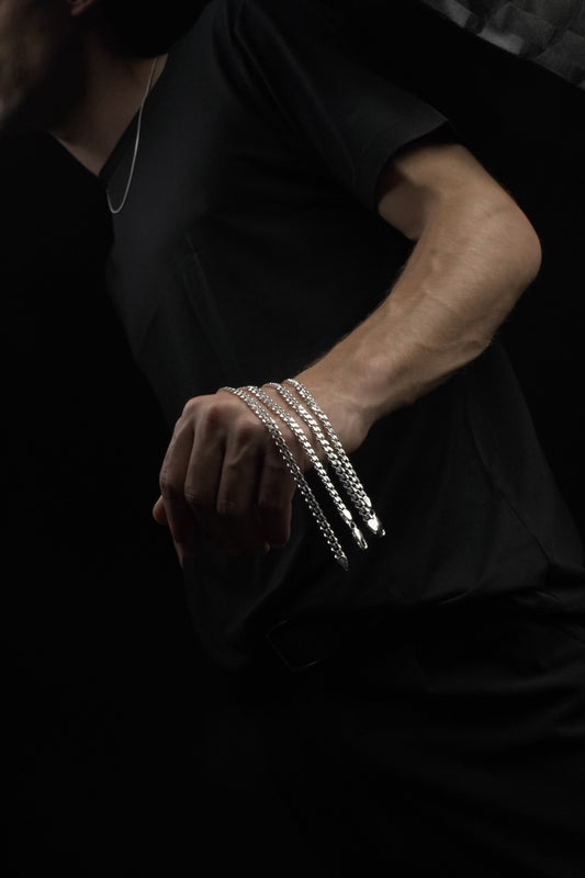 Close-up of a person's arm with multiple bracelets on a dark background