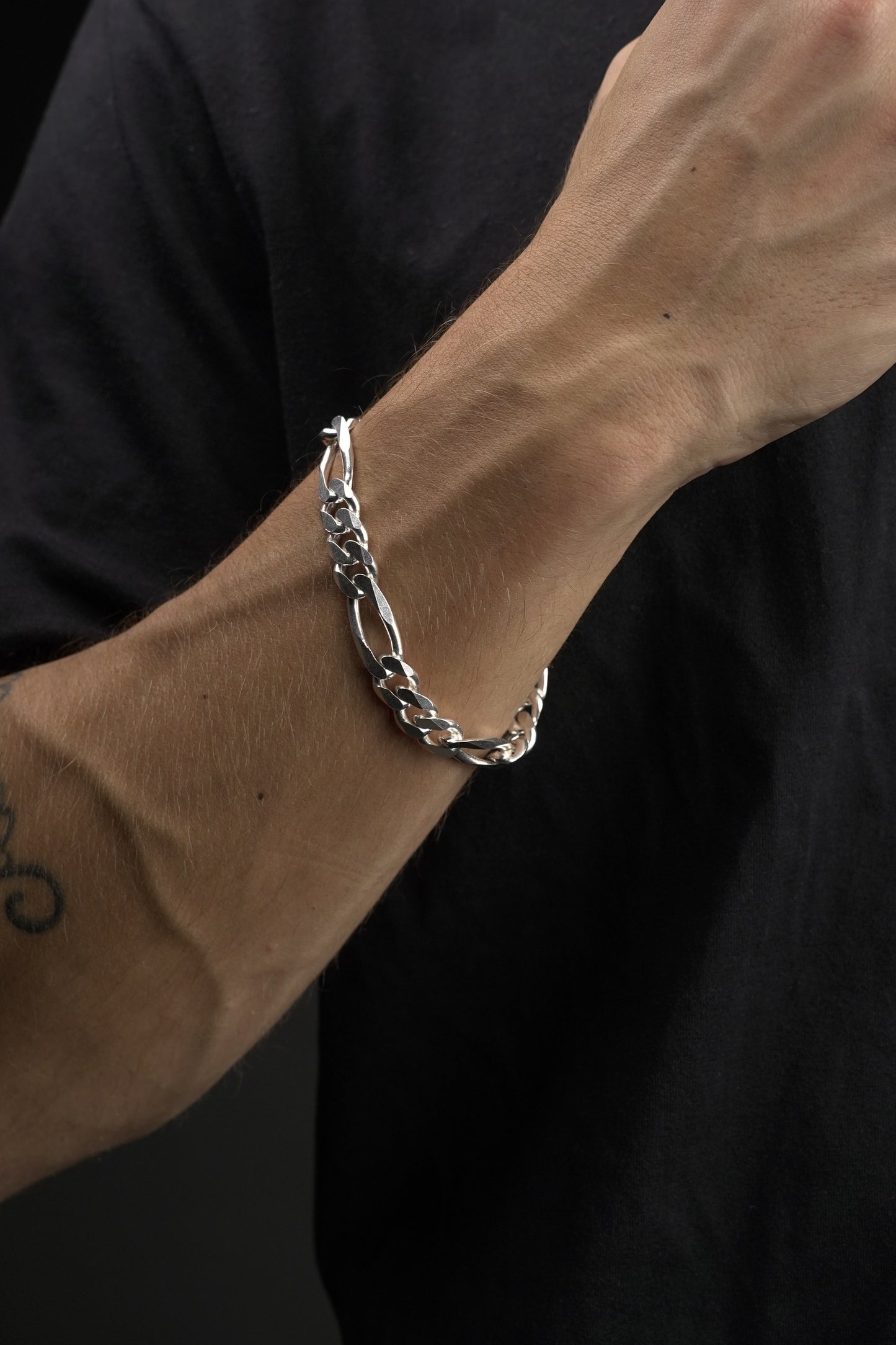 Silver bracelet on a wrist against a dark background