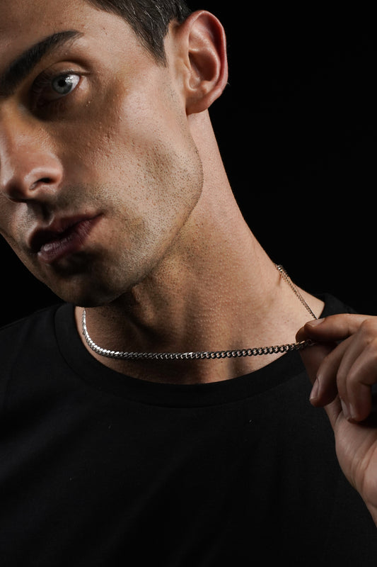 Man wearing a black shirt and chain necklace against a dark background