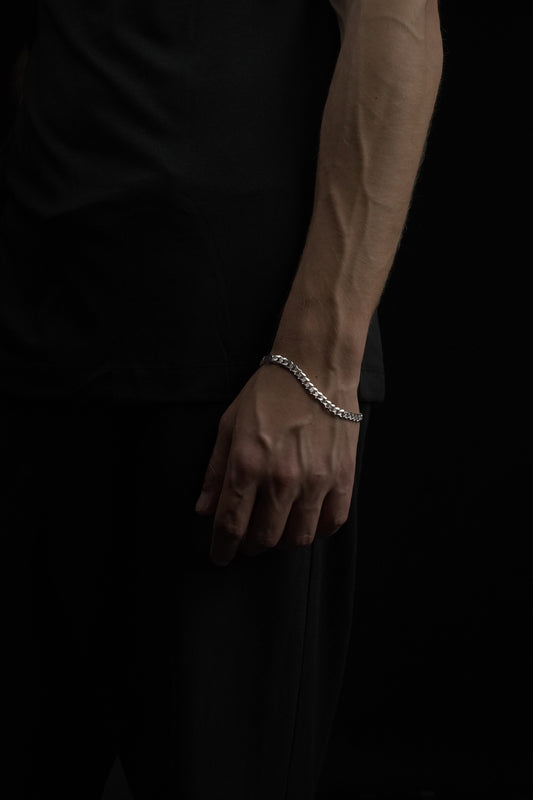 Hand wearing a silver bracelet on a dark background