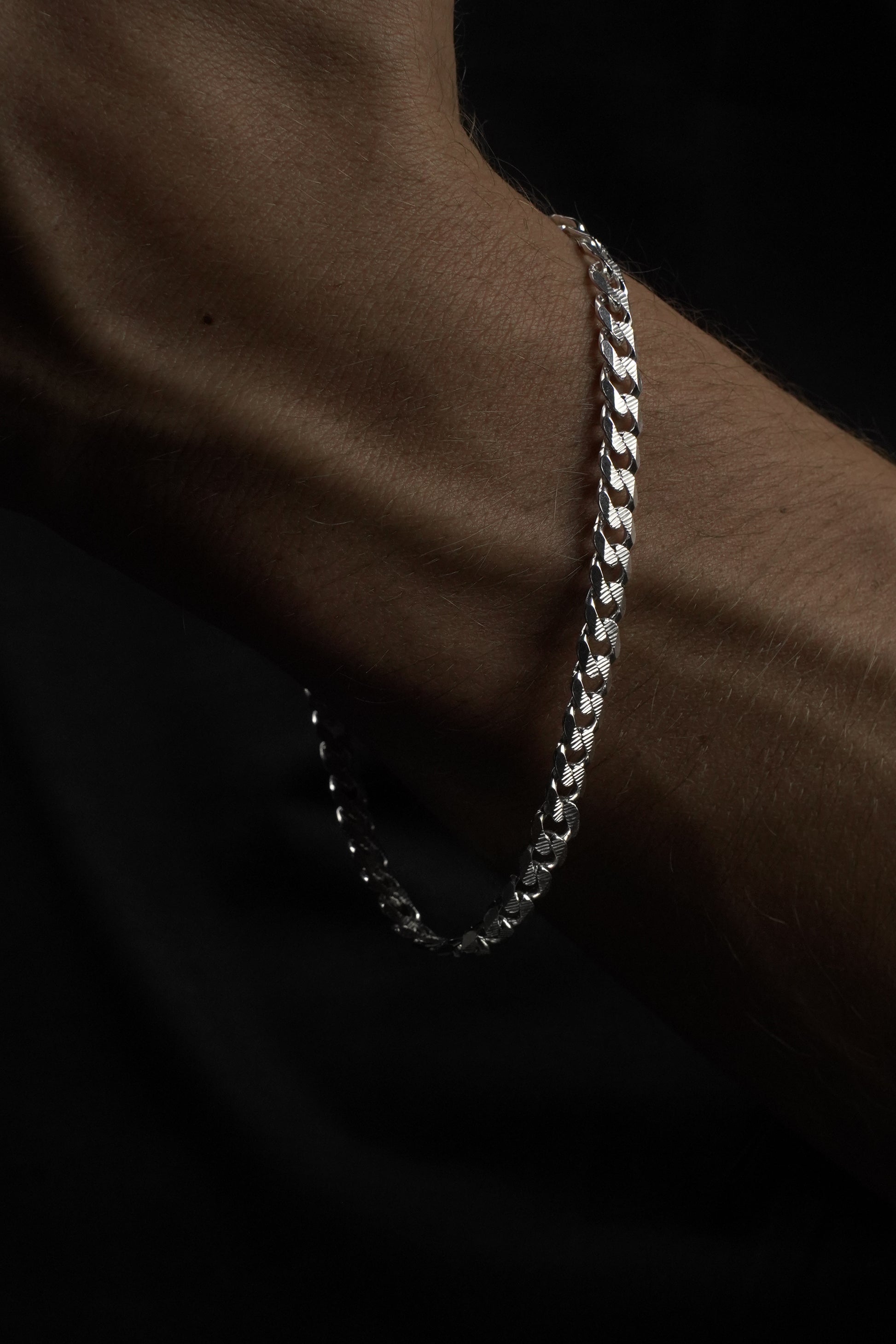 Silver bracelet on a wrist with a dark background