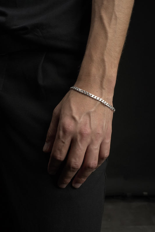 Hand wearing a silver bracelet on a dark background