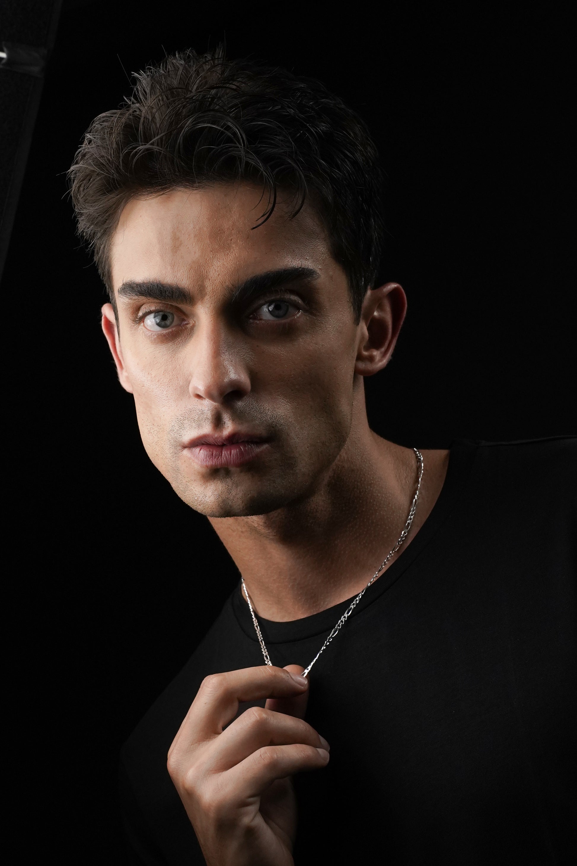 Man wearing a necklace against a black background