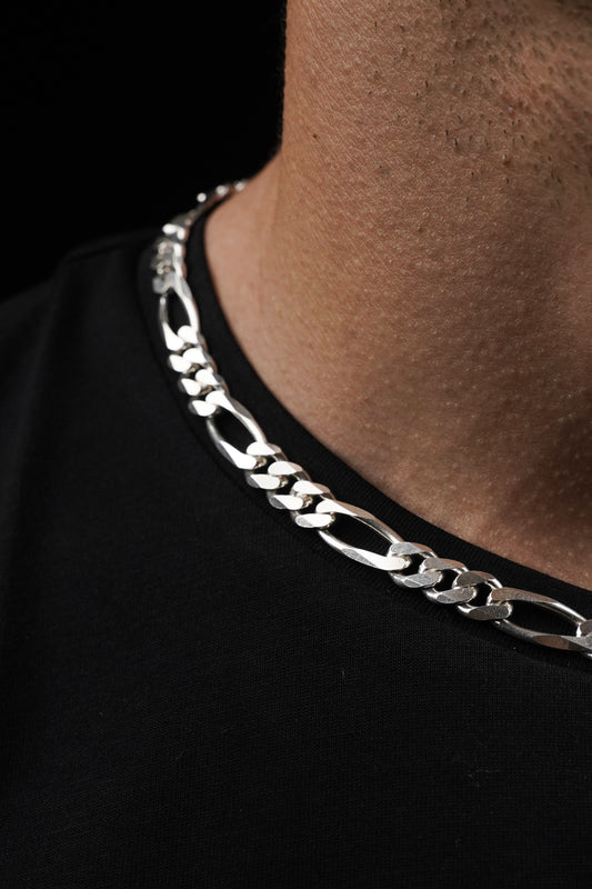 Silver chain necklace on a black shirt with a blurred background