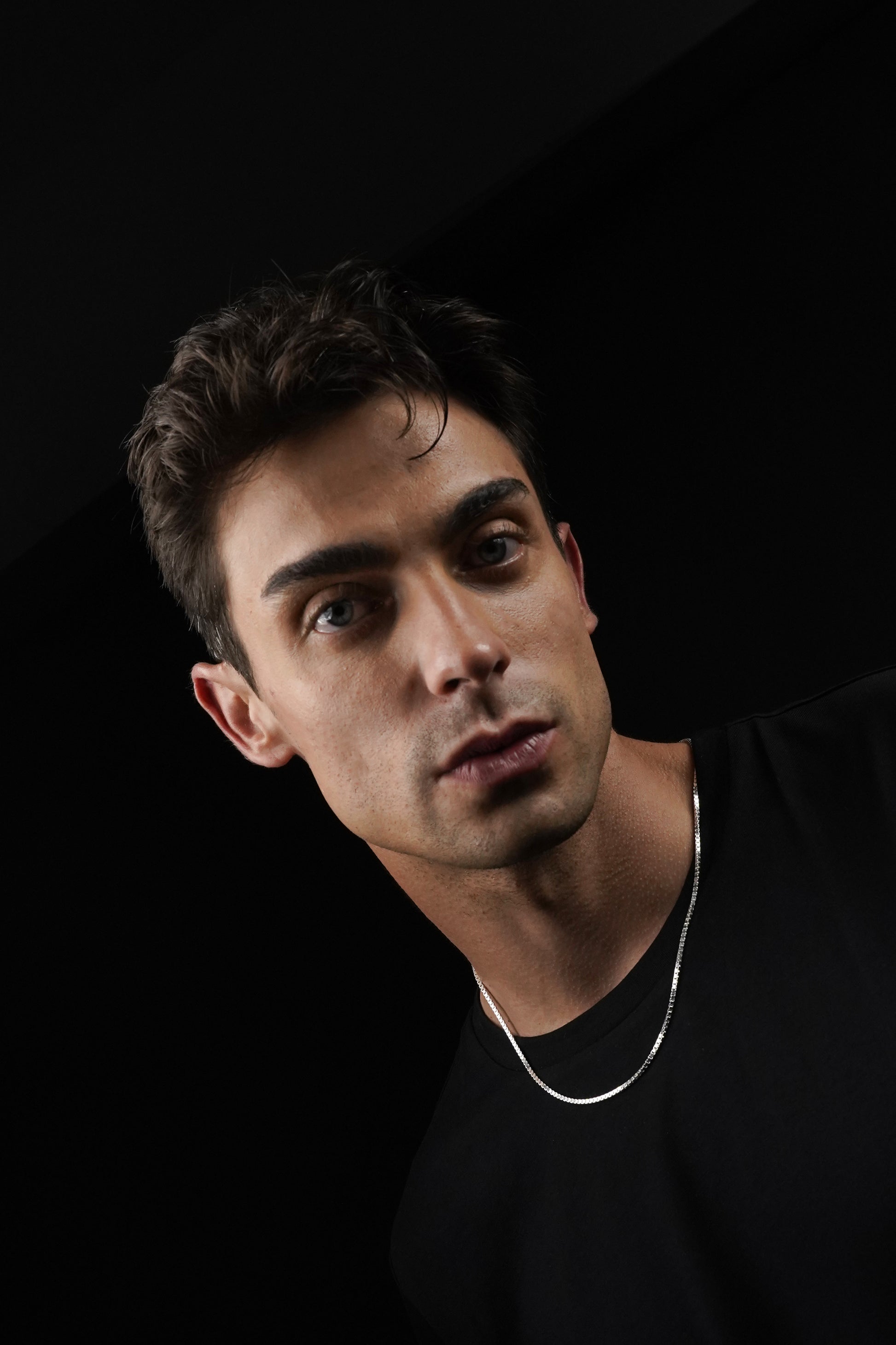 Man wearing a black shirt with a dark background