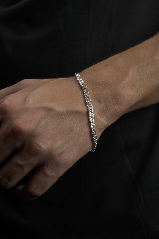 Silver chain bracelet on a wrist against a dark background