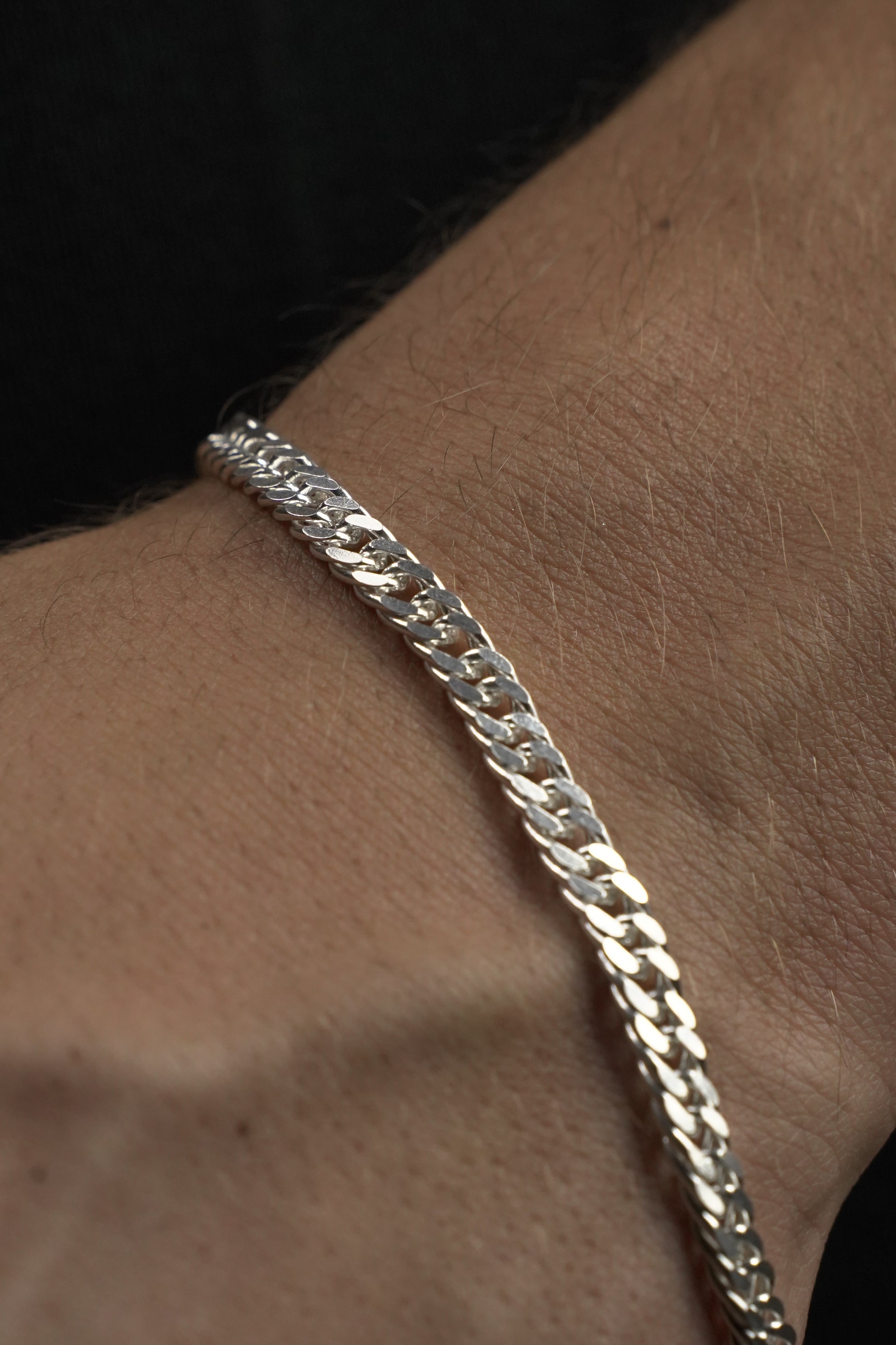 Close-up of a silver chain bracelet on a person's wrist.