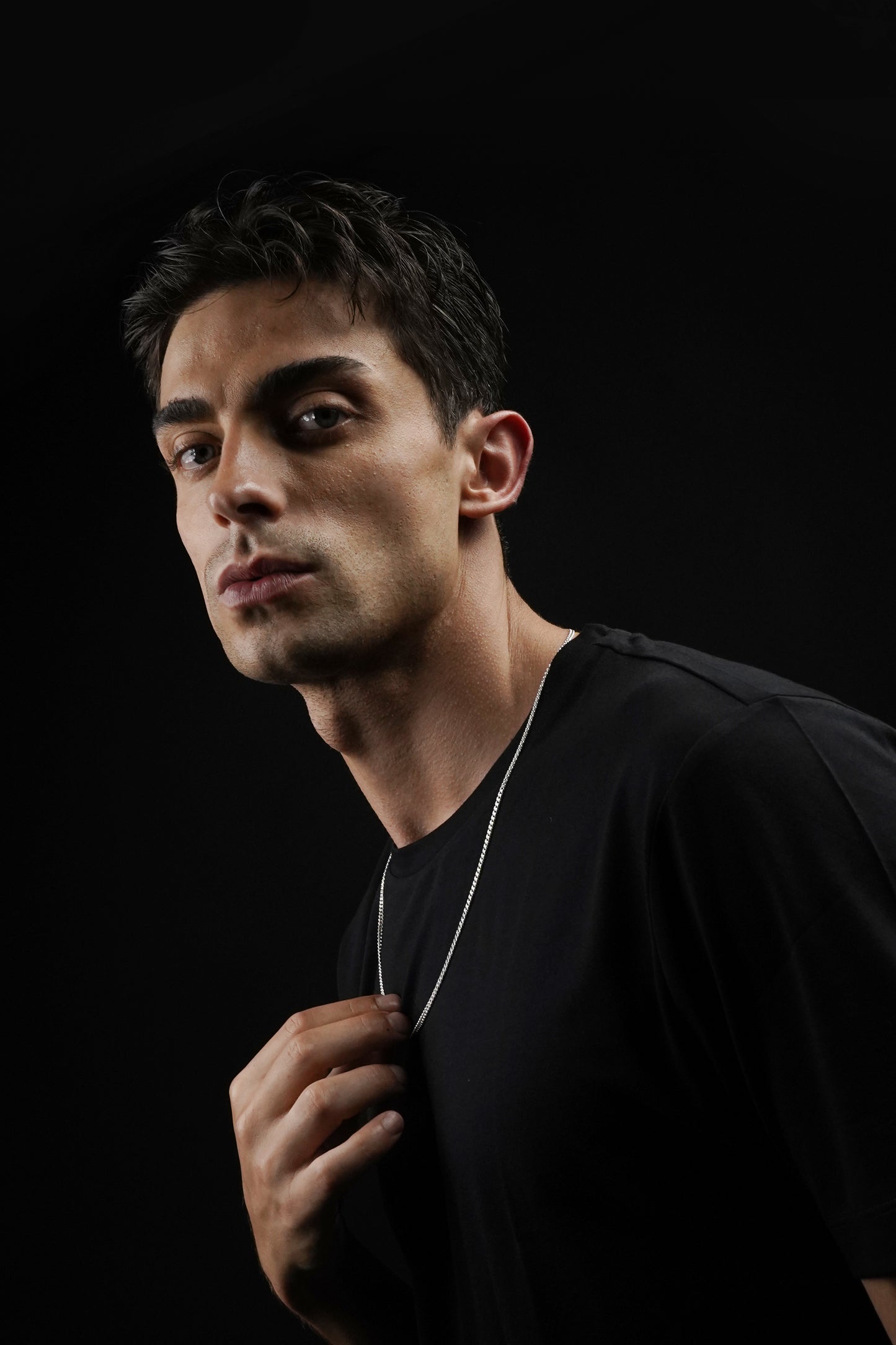 Man wearing a black shirt against a black background