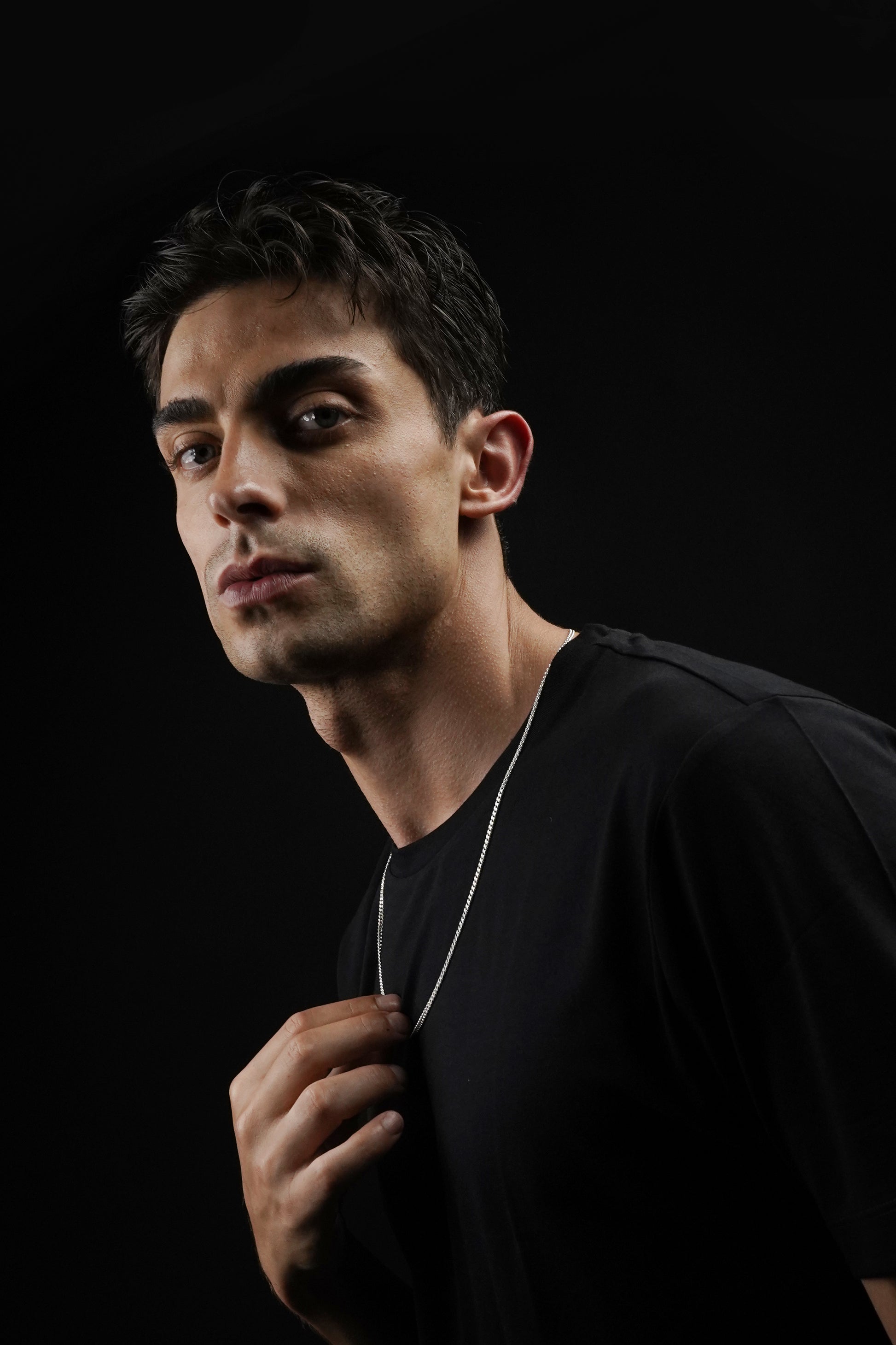 Man wearing a black shirt against a black background