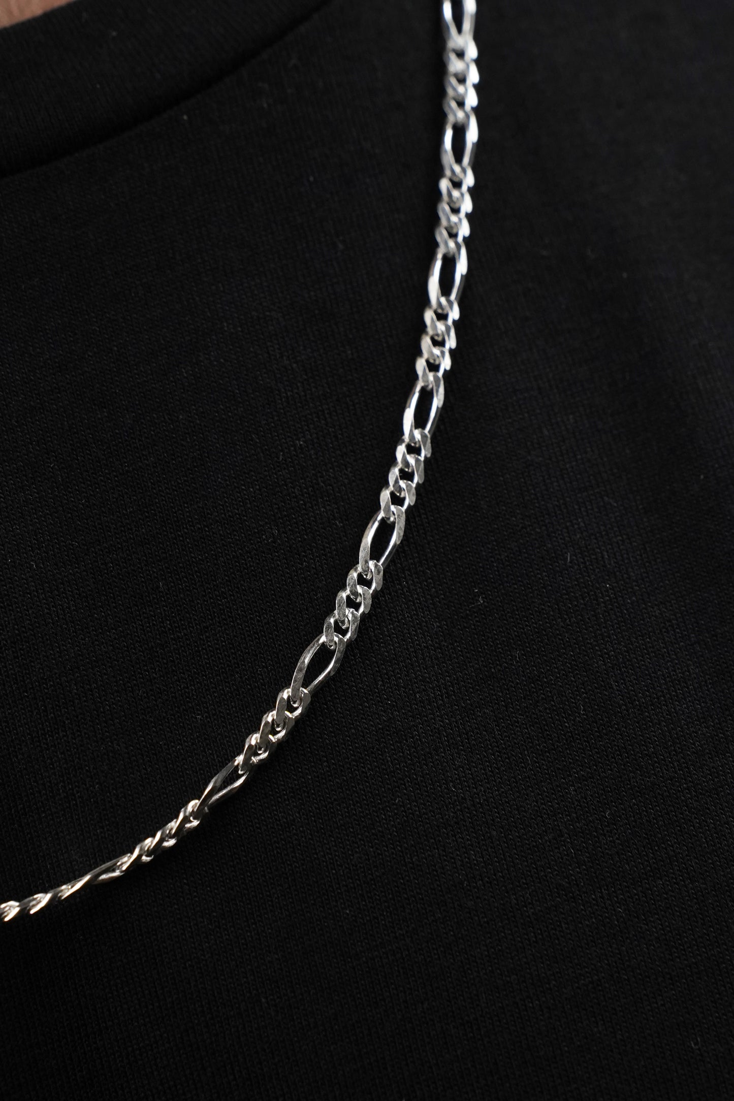 Silver chain necklace on a black background