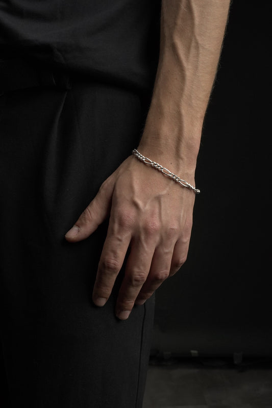 Hand wearing a silver bracelet on a dark background