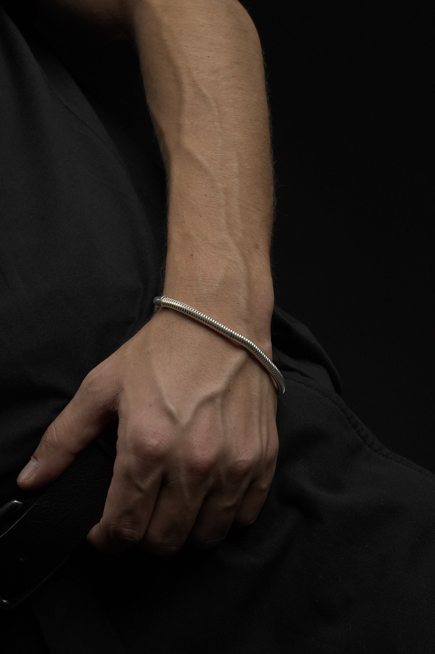 Close-up of a hand with a bracelet on a dark background