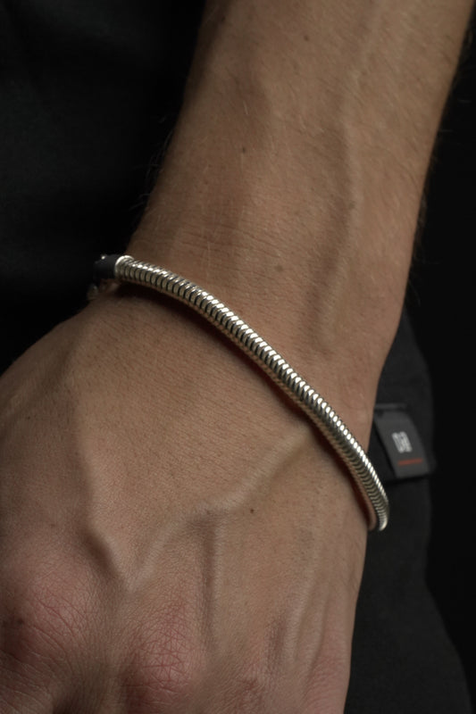 Close-up of a wrist wearing a silver bracelet on a dark background