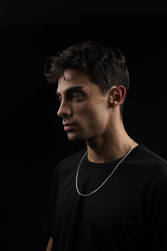 Man wearing a black shirt with white earphones on a dark background