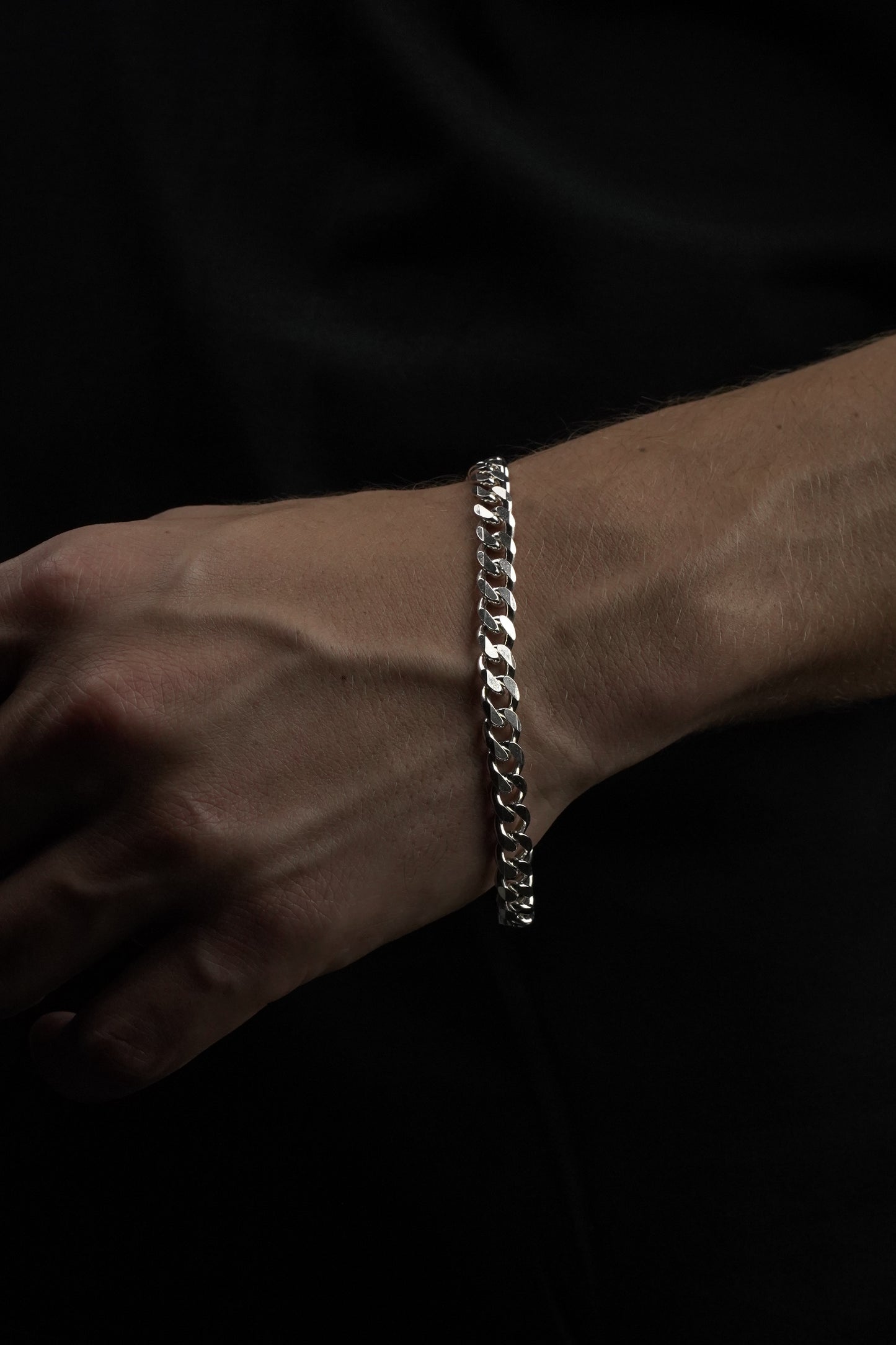 Silver bracelet on a wrist against a dark background