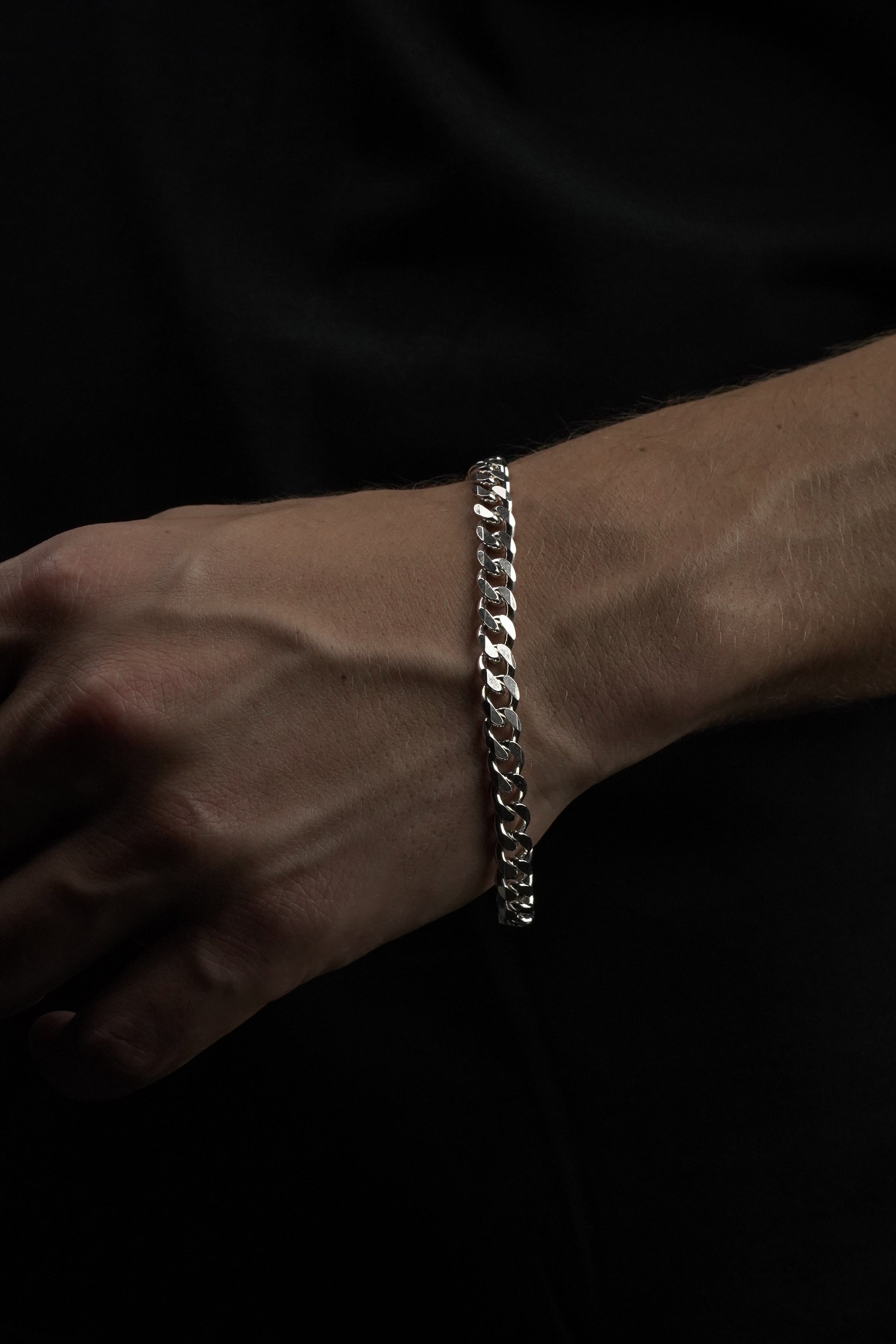 Silver bracelet on a wrist against a dark background