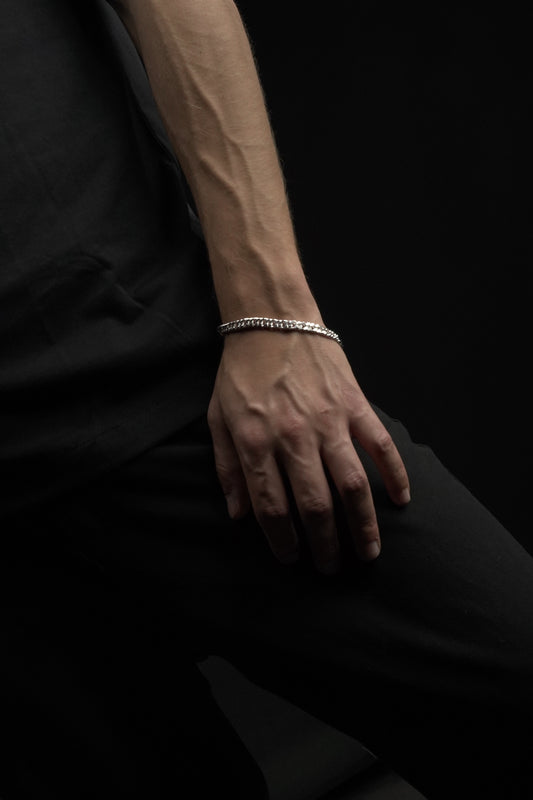 Hand wearing a bracelet on a dark background