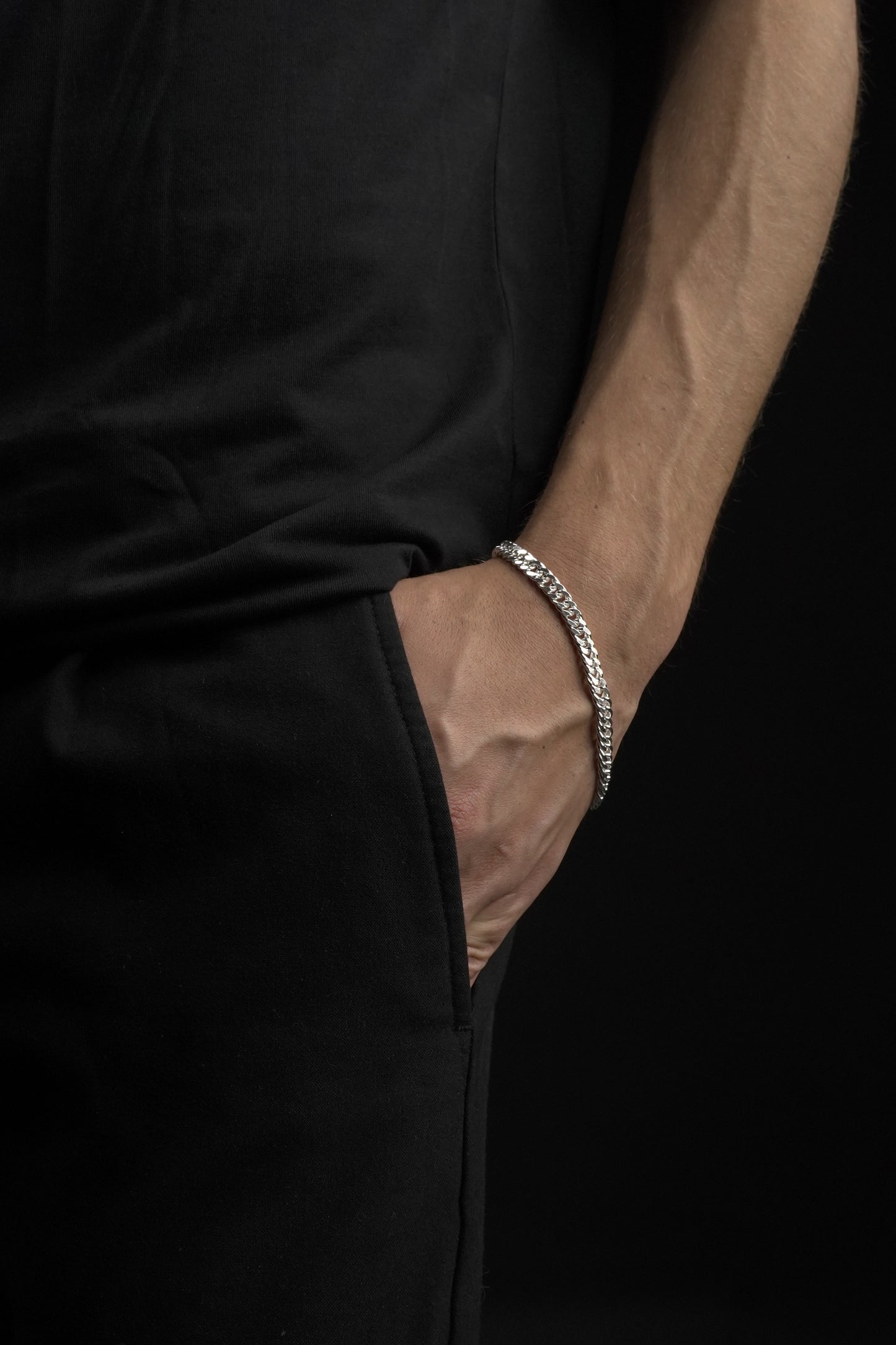 Close-up of a person's wrist wearing a silver bracelet with a dark background